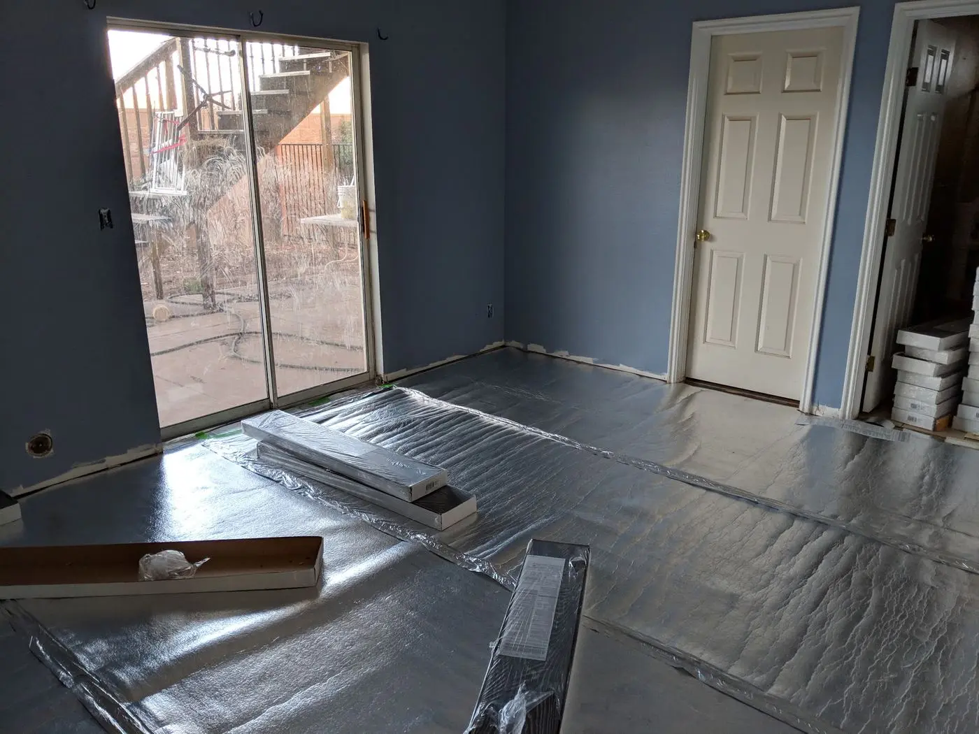 Before: bare subfloor with underlayment and prep material laid out, ready for new flooring